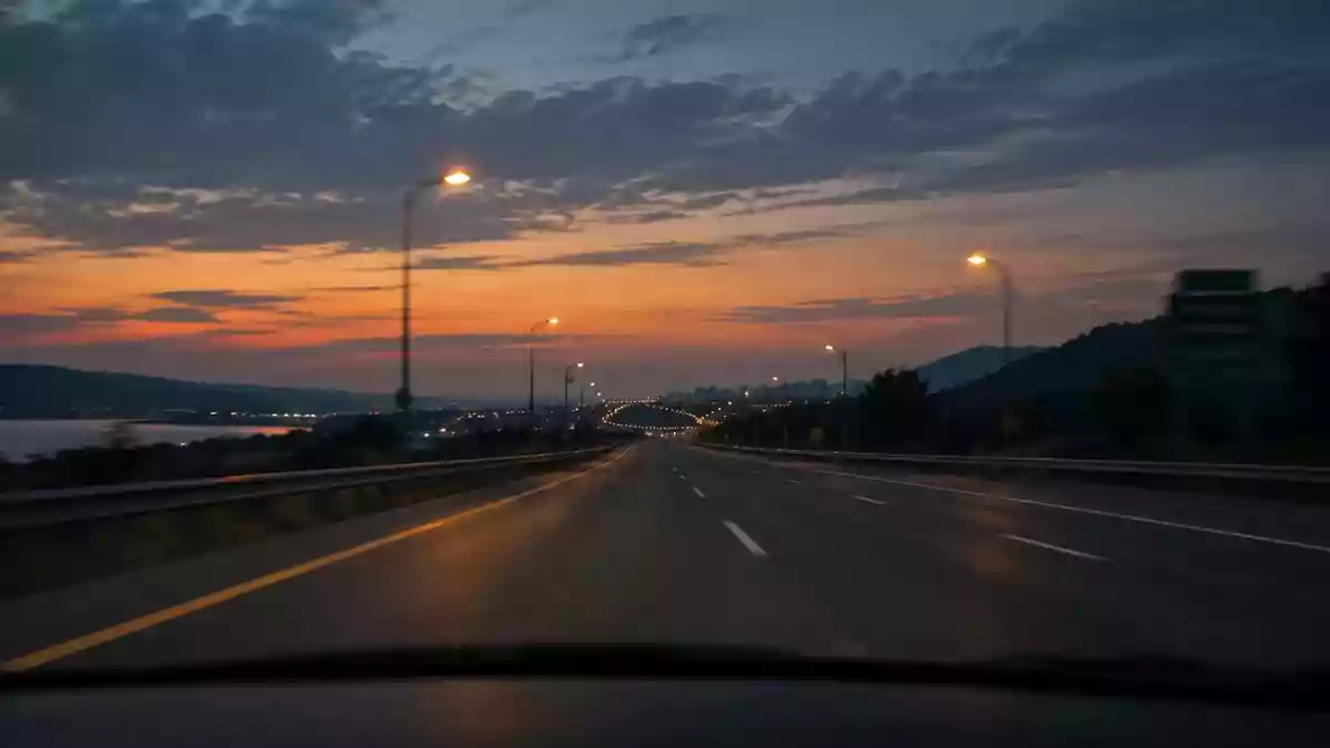 Blick durch eine Windschutzscheibe auf eine nächtliche Autobahn bei Dämmerung. Illustration mit AI erstellt.