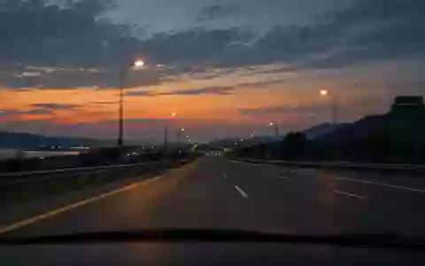 Blick durch eine Windschutzscheibe auf eine nächtliche Autobahn bei Dämmerung. - Foto: über boerse-global.de