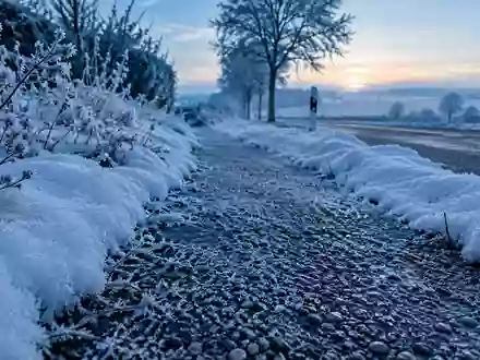 Verschneiter Gehweg an einem frostigen Wintermorgen in einer Wohngegend mit gefrorenem Streugut auf dem Boden. - Foto: über boerse-global.de