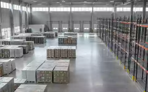 Ein weites, modernes Industrielager mit leeren Regalen und gestapelten Paletten in einer ruhigen, minimalistischen Umgebung. - Foto: über boerse-global.de