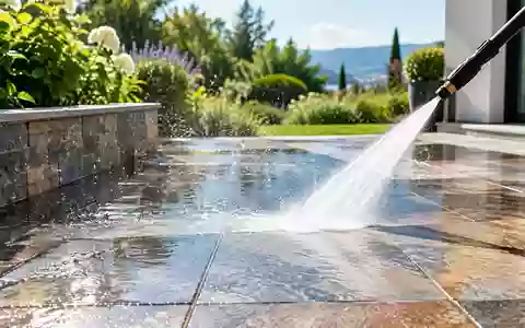 Ein sauberer Fliesenboden auf einer Terrasse wird mit einem Hochdruckreiniger gereinigt, wobei Wassertropfen im Sonnenlicht glänzen. - Foto: über boerse-global.de