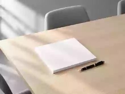 Ein minimalistischer, heller Konferenztisch mit einem Stapel leerer Papierblätter und einem Füllfederhalter bei Tageslicht. - Foto: über boerse-global.de