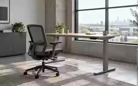 Ein leerer, ergonomischer Arbeitsplatz mit einem höhenverstellbaren Schreibtisch in einem hellen Büro. - Foto: über boerse-global.de