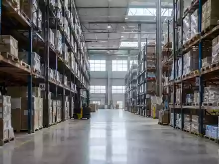 Innenansicht eines großen Logistikzentrums mit hohen Regalsystemen und Betonboden in einer Industriehalle. - Foto: über boerse-global.de