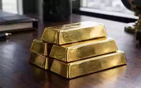 Ein Stapel Goldbarren auf einem dunklen Holztisch bei natürlichem Lichteinfall. - Foto: über boerse-global.de
