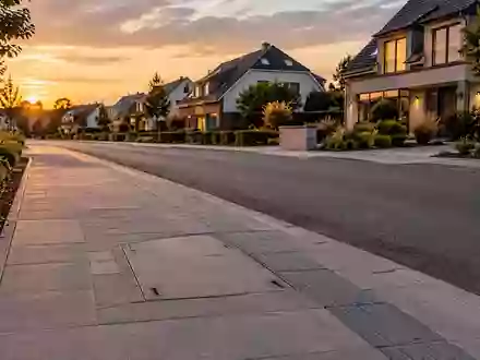 Eine ruhige Wohnstraße mit frisch verlegter Glasfaserinfrastruktur im Gehweg bei Dämmerung. - Foto: über boerse-global.de
