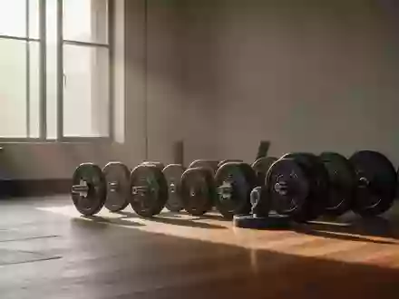 Leeres, minimalistisches Fitnessstudio mit ordentlich gestapelten Hantelscheiben auf einem Holzboden in natürlichem Licht. - Foto: über boerse-global.de