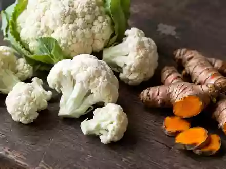 Frischer Blumenkohl und Kurkumawurzeln auf einer dunklen Holzoberfläche in natürlichem Licht. - Foto: über boerse-global.de