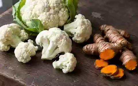 Frischer Blumenkohl und Kurkumawurzeln auf einer dunklen Holzoberfläche in natürlichem Licht. - Foto: über boerse-global.de