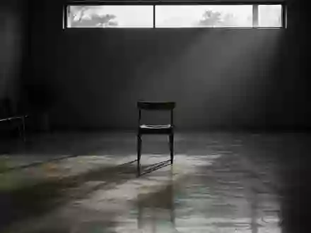 Ein leerer, minimalistischer Wartebereich mit einem einzelnen Holzstuhl in einem Raum mit gedämpftem Licht und langen Schatten. - Foto: über boerse-global.de