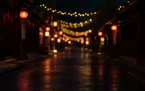 Dunkle, nächtliche Stadtstraße mit unscharfen, festlichen Lichterketten und Laternen im Hintergrund. - Foto: über boerse-global.de