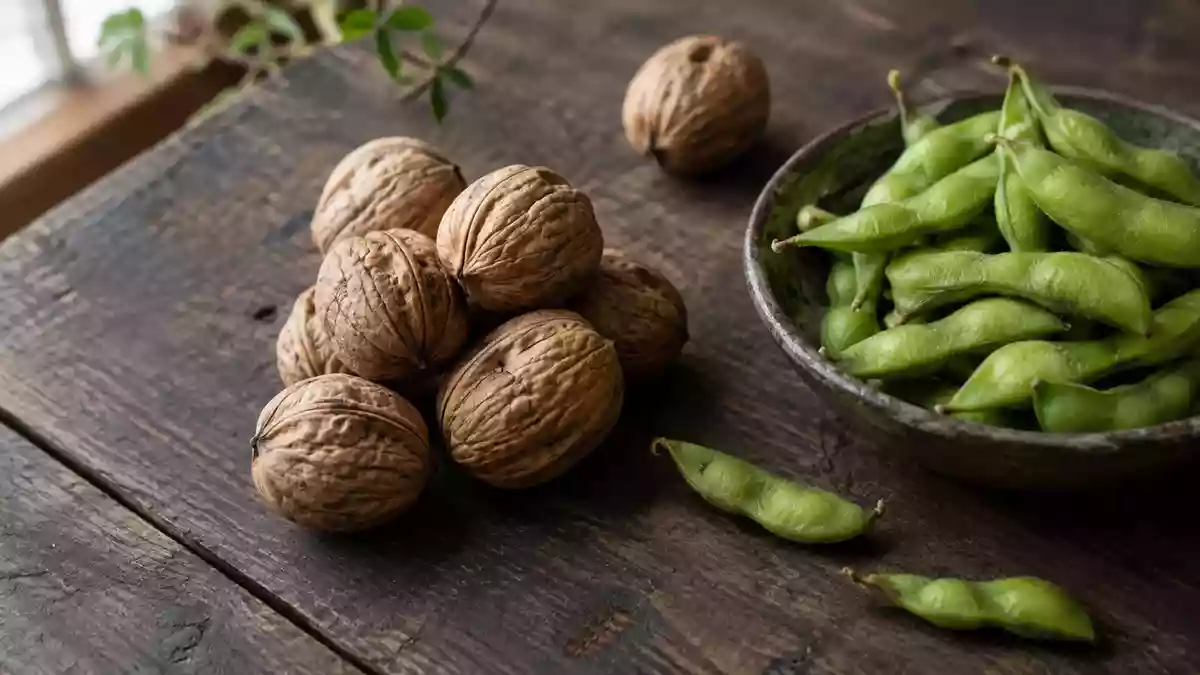 Nahaufnahme von Walnüssen in der Schale und grünen Edamame-Schoten auf einem rustikalen Holztisch bei natürlichem Licht. Illustration mit AI erstellt.