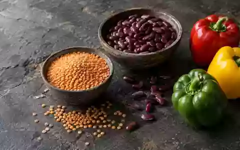 Rohkost wie Linsen, Bohnen und Paprika auf einem dunklen Steintisch bei natürlichem Licht. - Foto: über boerse-global.de