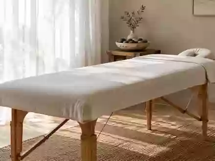 Ein minimalistischer Behandlungsraum mit einer leeren Massageliege und glatten Flusskieselsteinen in weichem Licht. - Foto: über boerse-global.de
