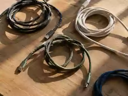 Verschiedene Ladekabel ordentlich auf einer hölzernen Werkbank arrangiert bei natürlichem Lichteinfall. - Foto: über boerse-global.de