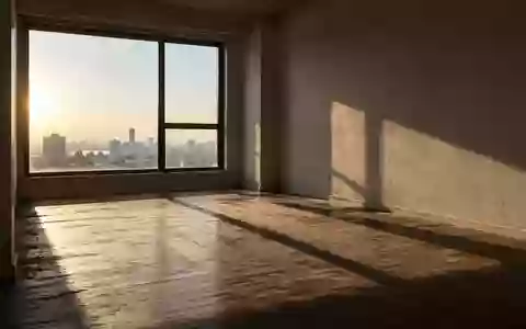 Ein leerer, sonnendurchfluteter Wohnraum mit kahlen Wänden und Holzboden in einer minimalistischen Wohnung. - Foto: über boerse-global.de