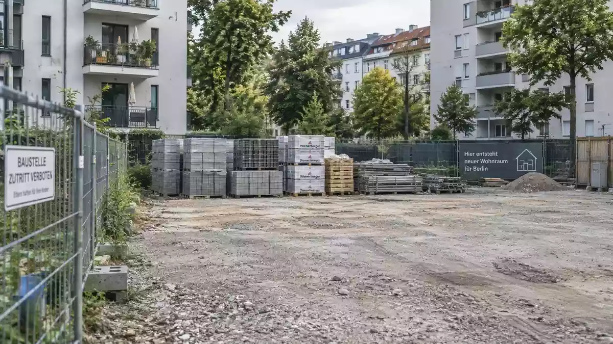 Eine freigeräumte Baufläche in einer innerstädtischen Wohngegend mit Bauzäunen und Baumaterialien bei natürlichem Tageslicht. Illustration mit AI erstellt.