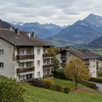 Ältere Mehrfamilienhäuser in einer Siedlung vor einer alpinen Bergkulisse in Bad Wiessee. - Foto: über boerse-global.de