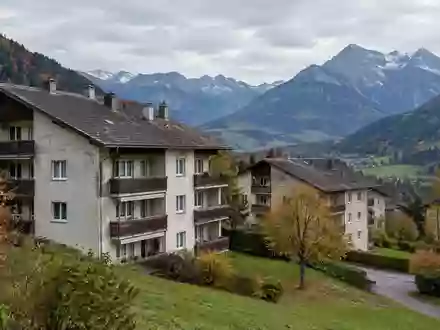 Ältere Mehrfamilienhäuser in einer Siedlung vor einer alpinen Bergkulisse in Bad Wiessee. - Foto: über boerse-global.de