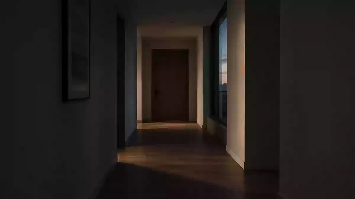 Ein schmaler, in dämmriges Licht getauchter Flur mit einer geschlossenen Tür am Ende, der eine Atmosphäre von Anonymität vermittelt. Illustration mit AI erstellt.