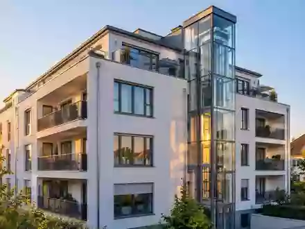 Modernes Wohngebäude mit klaren architektonischen Linien und Aufzugsschacht in einem deutschen Wohnviertel. - Foto: über boerse-global.de