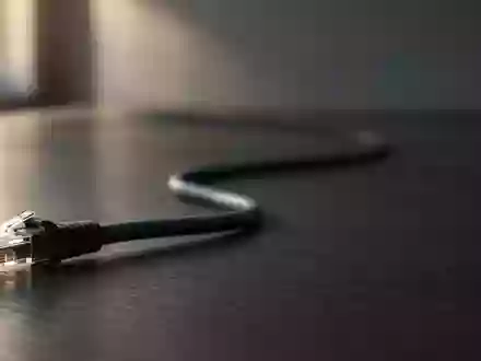 Ein Ethernet-Kabel auf einem dunklen Schreibtisch vor unscharfem Hintergrund. - Foto: über boerse-global.de