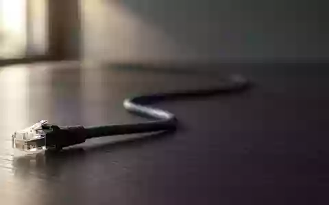 Ein Ethernet-Kabel auf einem dunklen Schreibtisch vor unscharfem Hintergrund. - Foto: über boerse-global.de