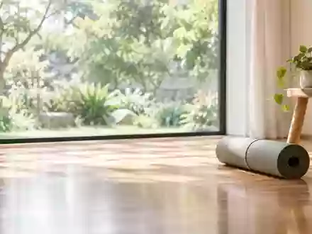 Ein heller Raum mit Holzboden und einer zusammengerollten Yogamatte vor einem Fenster mit Blick ins Grüne. - Foto: über boerse-global.de
