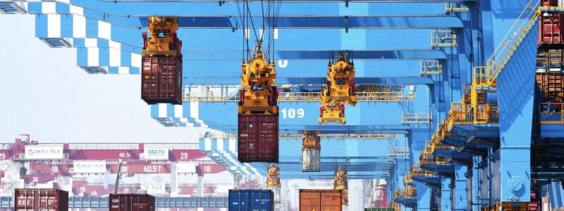 Portalkräne bewegen Container auf Transporter in einem Hafen in Qingdao in der ostchinesischen Provinz Shandong. - Foto: Uncredited/CHINATOPIX/dpa