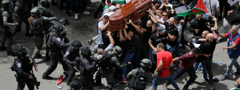 Israelische Polizisten stoßen mit palästinensischen Trauernden zusammen, die den Sarg der getöteten Al-Dschasira-Reporterin tragen. - Foto: Maya Levin/AP/dpa