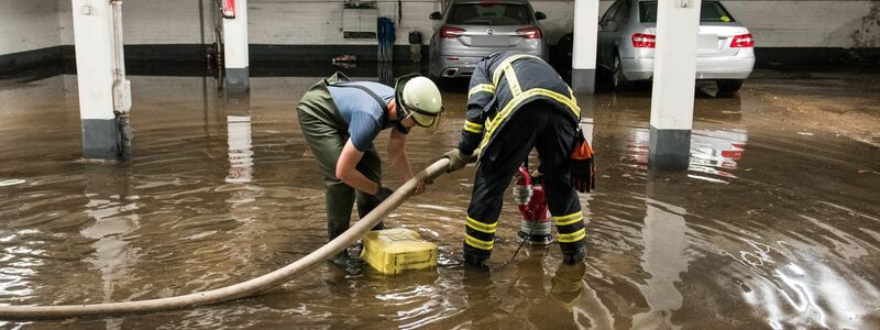 Feuerwehrleute pumpen in Hamburg Wasser aus einer überfluteten Tiefgarage ab. - Foto: Daniel Bockwoldt/dpa