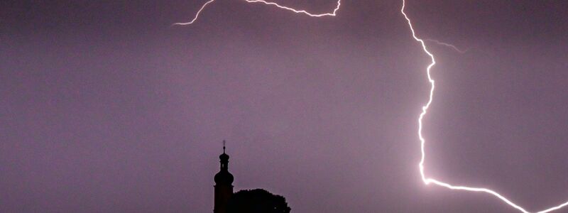 Blitze entladen sich aus einer Gewitterwolke über der Pfarrkirche im bayrischen Straubing. - Foto: Armin Weigel/dpa