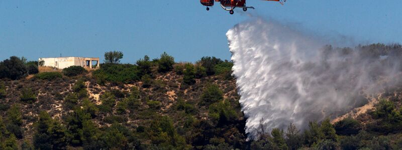 Ein Löschhubschrauber löscht einen Waldbrand in Griechenland. - Foto: Marios Lolos/XinHua/dpa