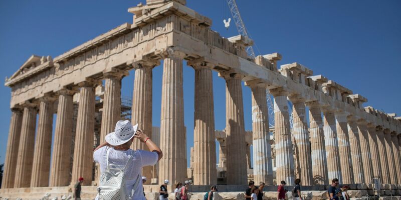 Touristen spazieren auf dem Lycabettus-Hügel, während der Himmel über Athen mit dem antiken Akropolis-Hügel im Hintergrund infolge von Saharastaub eingetrübt ist. - Foto: Petros Giannakouris/AP/dpa