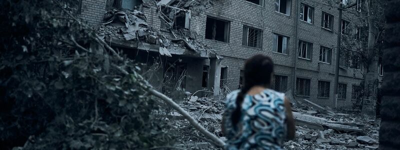 Eine Frau steht inmitten der Trümmer eines Wohnhauses in Mykolajiw, das durch russischen Beschuss zerstört wurde. - Foto: Kostiantyn Liberov/AP/dpa