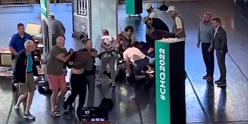 Menschen kümmern sich um den verletzten Rushdie, während ein Mann von der Bühne eskortiert wird. (Aufnahme kurz nach dem Angriff) - Foto: Uncredited/AP/dpa