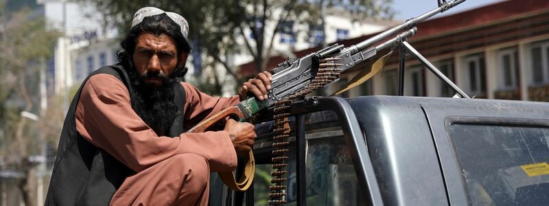 Ein Taliban-Kämpfer sitzt in Kabul mit einem Maschinengewehr auf der Ladefläche eines Fahrzeugs. - Foto: -/AP/dpa