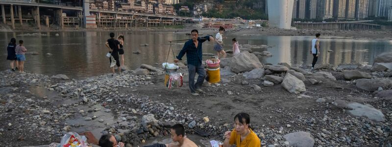 China kämpft gegen die Dürre. Menschen sitzen in einem flachen Wasserbecken im Flussbett des Jialing-Flusses, einem Nebenfluss des Jangtse, in der südwestchinesischen Stadt Chongqing. - Foto: Mark Schiefelbein/AP/dpa