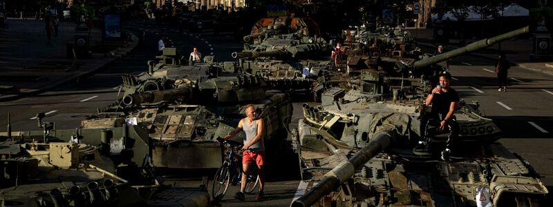 Menschen inspizieren zerstörte russische Militärfahrzeuge, die in der Innenstadt von Kiew aufgestellt sind. - Foto: Evgeniy Maloletka/AP/dpa