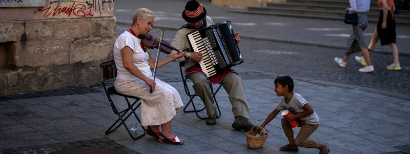Ein Kind versucht, zwei Straßenmusikern in der Innenstadt von Lwiw Geld zu stehlen. - Foto: Emilio Morenatti/AP/dpa