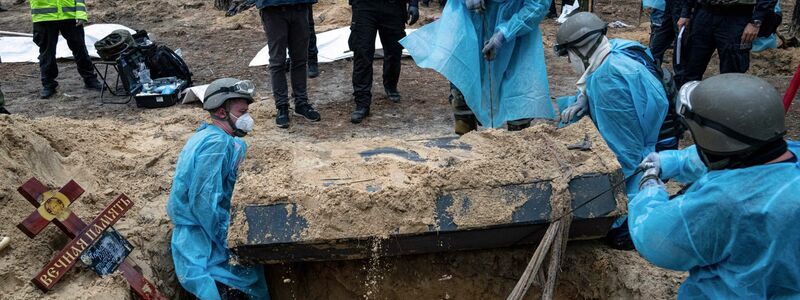 Ukrainische Rettungskräfte bergen bei der Exhumierung in Isjum einen Sarg. - Foto: Evgeniy Maloletka/AP/dpa
