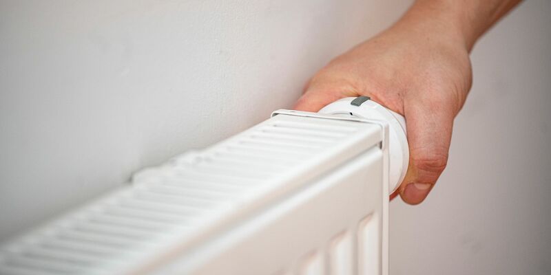 Eine Person benutzt einen alten Heizkörper in einer Berliner Altbauwohnung. - Foto: Fabian Sommer/dpa