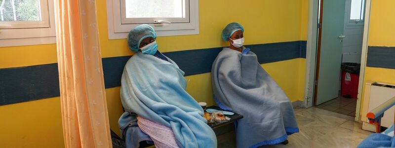 Zwei Frauen sitzen nach ihrer Rettung in Decken gewickelt zur Behandlung in einem Krankenhaus auf Lesbos. - Foto: Panagiotis Balaskas/AP/dpa