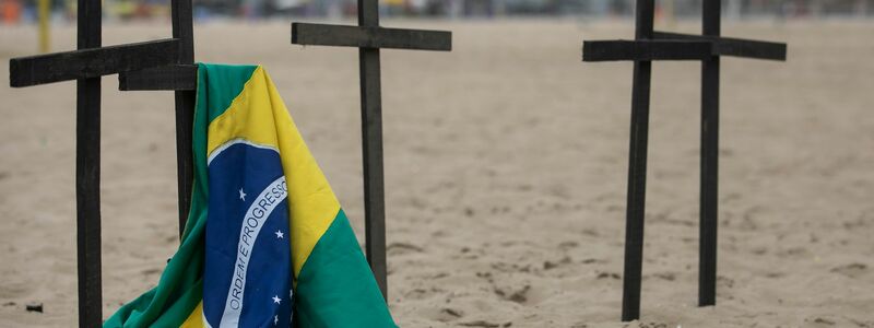 Eine brasilianische Flagge hängt an der Copacabana an einem der Kreuze bei einer Gedenkveranstaltung für einen ungewöhnlichen Corona-Protest. - Foto: Bruna Prado/AP/dpa