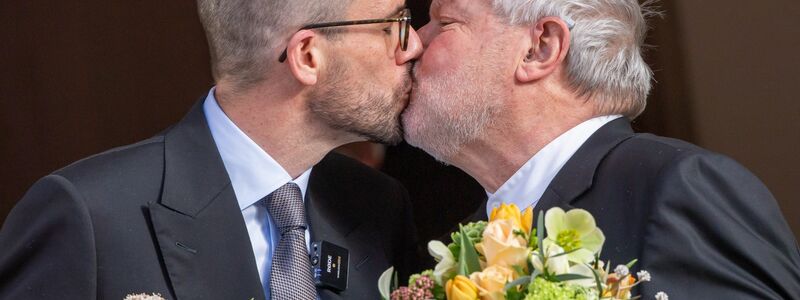 Der ehemalige Benediktiner-Mönch Anselm Bilgri und sein Mann Markus küssen sich 2021 nach ihrer standesamtlichen Trauung. - Foto: Peter Kneffel/dpa