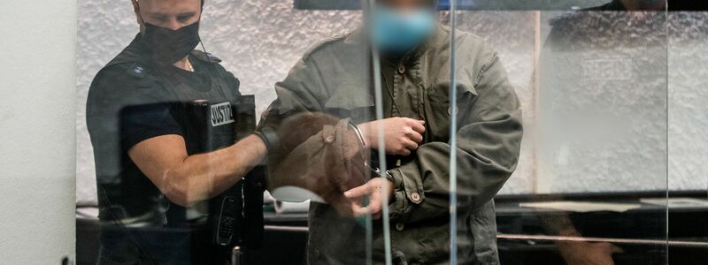 Ein Justizbeamter führt den Angeklagten (r) zu seinem Platz im Gericht. - Foto: Christoph Schmidt/dpa