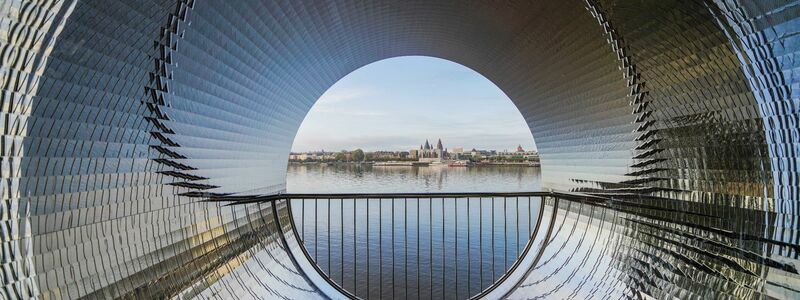 Die Edelstahloberfläche der «Pixelröhre» spiegelt die Landschaft und das Wasser am Rheinufer im Stadtteil Kastel wieder. - Foto: Andreas Arnold/dpa