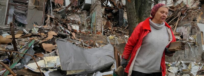 Anwohnerin Nina (72) trägt in Slowjansk hölzerne Trümmer in der Nähe ihres Hauses, das durch Beschuss vor einem Monat zerstört wurde. - Foto: Efrem Lukatsky/AP/dpa
