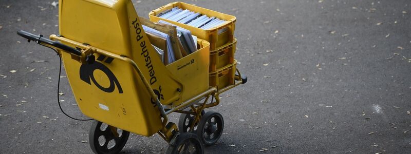 Ein Trolley eines Zustellers der Deutschen Post steht auf der Straße. - Foto: Lino Marcel Mirgeler/dpa