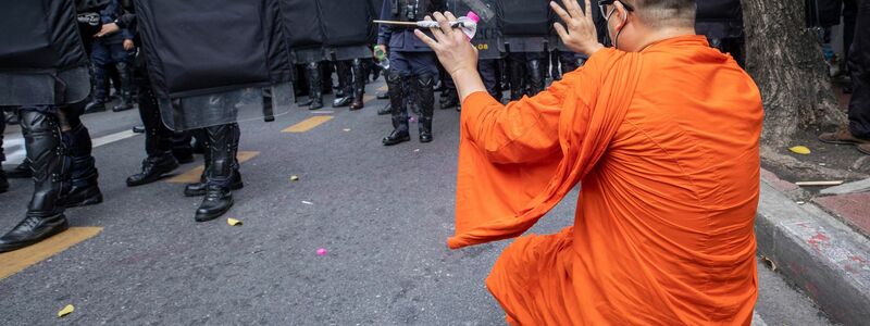 Ein Mönch hebt die Hände, als die Polizei Demonstrierende auseinandertreibt. - Foto: Wason Wanichakorn/AP/dpa
